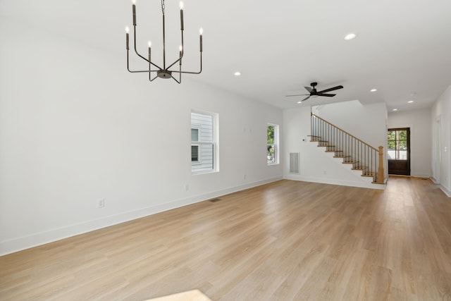 unfurnished living room with ceiling fan with notable chandelier and light hardwood / wood-style floors