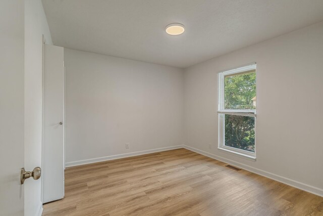 spare room featuring light wood-style flooring, baseboards, and visible vents