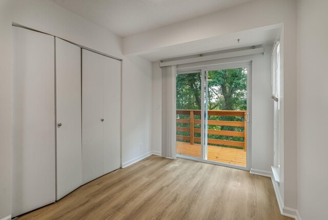 unfurnished bedroom featuring access to outside, light hardwood / wood-style flooring, and a closet