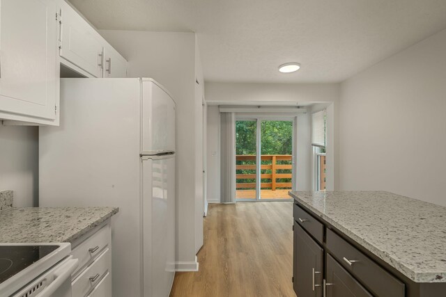 kitchen with light hardwood / wood-style flooring, light stone countertops, white appliances, and white cabinetry