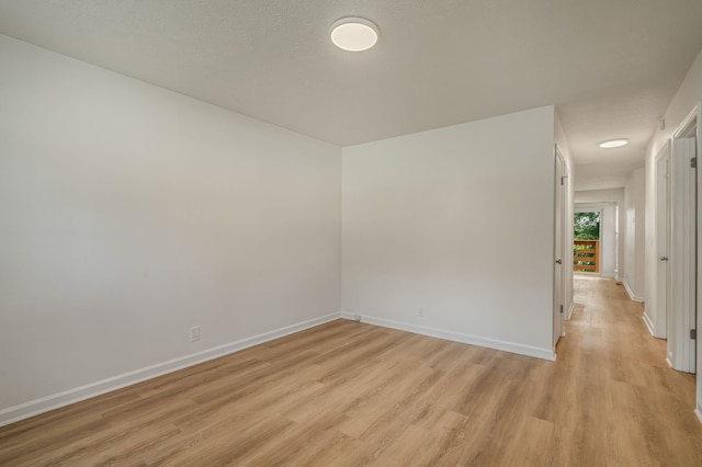 unfurnished room with baseboards and light wood-style floors