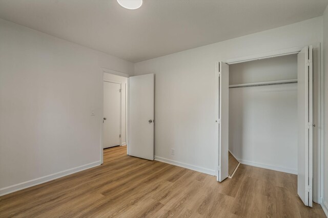 unfurnished bedroom featuring light hardwood / wood-style flooring and a closet