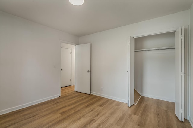 unfurnished bedroom featuring light wood-style flooring, baseboards, and a closet