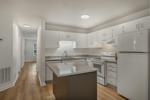 kitchen with white appliances, visible vents, a sink, under cabinet range hood, and a center island