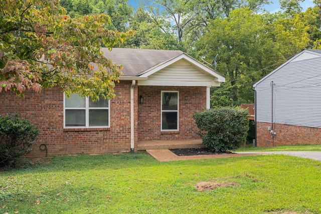 view of front facade featuring brick siding, a shingled roof, and a front yard