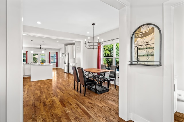 dining space featuring ceiling fan with notable chandelier, wood-type flooring, and a wealth of natural light