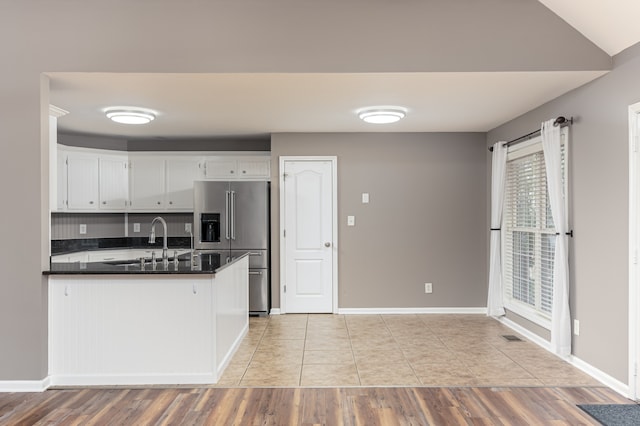 kitchen featuring sink, kitchen peninsula, stainless steel fridge, white cabinets, and light wood-type flooring