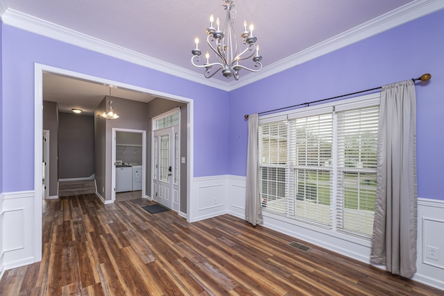 unfurnished dining area featuring washing machine and dryer, crown molding, dark hardwood / wood-style flooring, and a notable chandelier