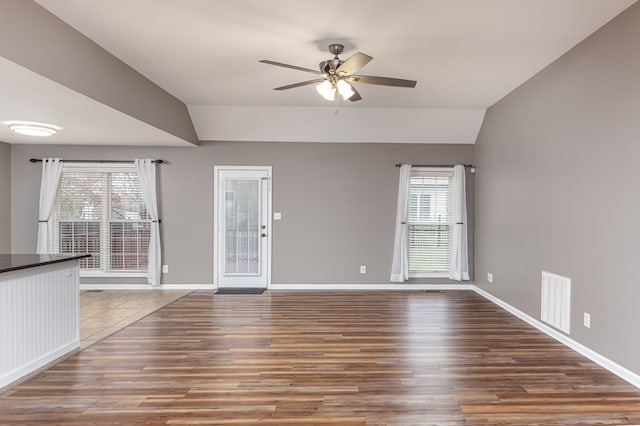 unfurnished room featuring a wealth of natural light, dark hardwood / wood-style flooring, ceiling fan, and lofted ceiling