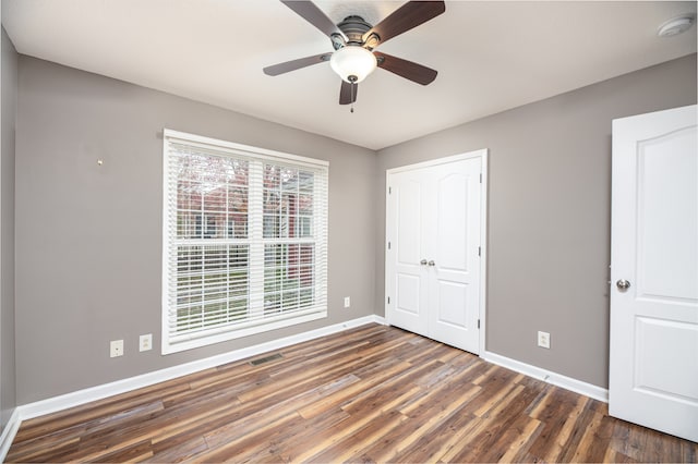 unfurnished bedroom featuring ceiling fan, dark hardwood / wood-style flooring, and a closet