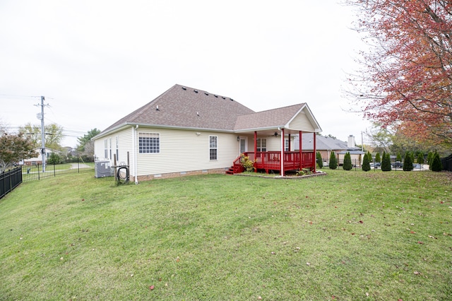 back of property with ceiling fan, a deck, and a yard