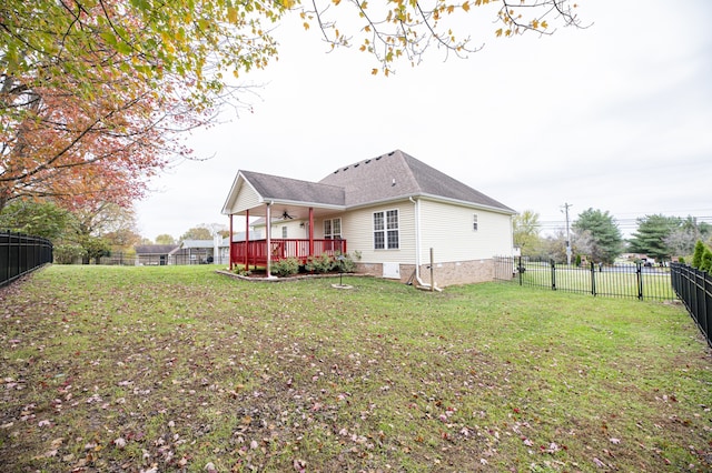 rear view of property with ceiling fan, a deck, and a yard