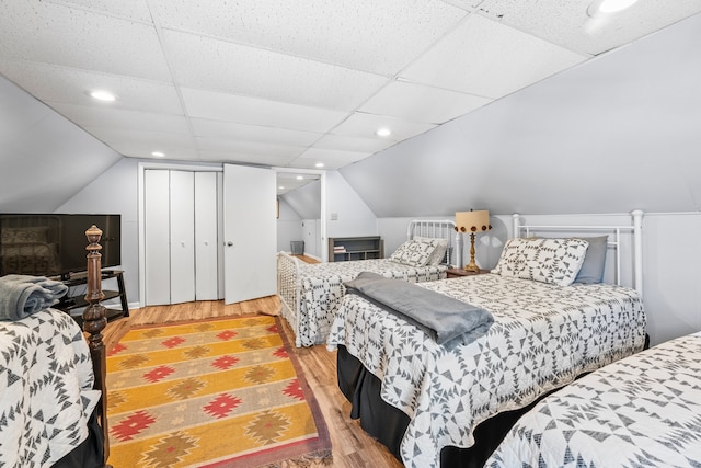 bedroom with vaulted ceiling, hardwood / wood-style floors, and a drop ceiling