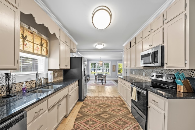 kitchen featuring appliances with stainless steel finishes, crown molding, sink, decorative backsplash, and dark stone counters