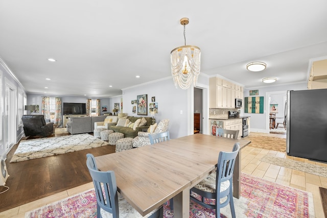 dining room featuring light wood-type flooring, ornamental molding, and a chandelier