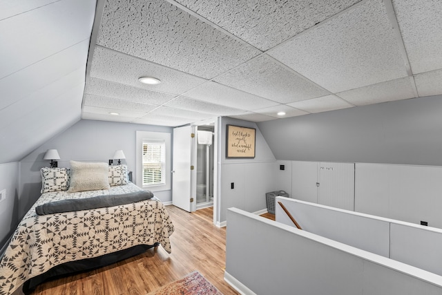 bedroom featuring lofted ceiling, light hardwood / wood-style floors, and a drop ceiling