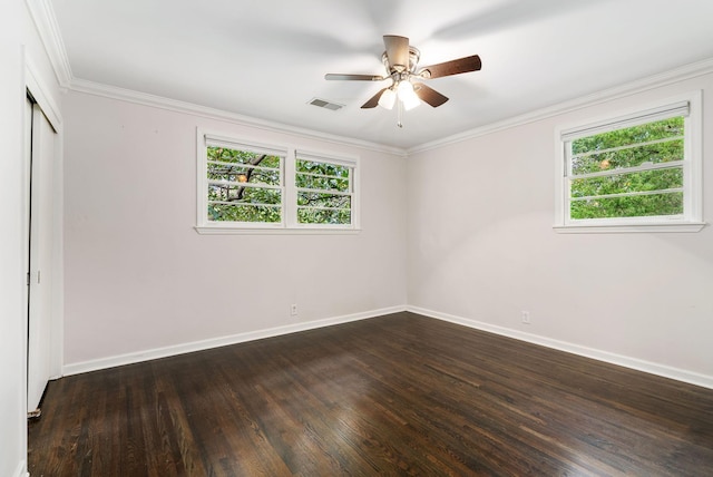 unfurnished room with dark wood finished floors, a healthy amount of sunlight, visible vents, and ornamental molding