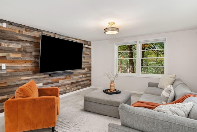 living room featuring carpet flooring, baseboards, wooden walls, and an accent wall