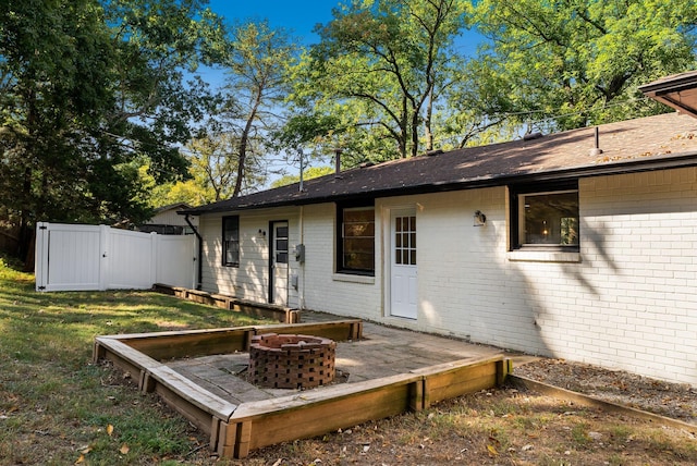 wooden terrace with a fire pit, a lawn, and fence