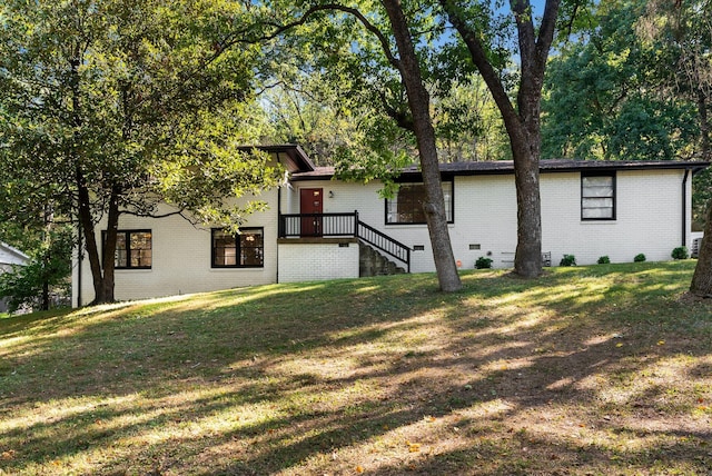 view of front of property featuring brick siding, crawl space, and a front yard