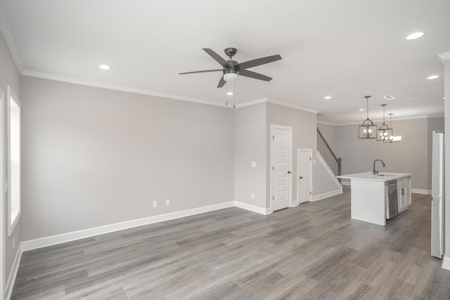 unfurnished living room featuring ceiling fan with notable chandelier, crown molding, wood-type flooring, and sink