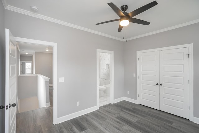 unfurnished bedroom featuring crown molding, ensuite bath, a closet, dark wood-type flooring, and ceiling fan