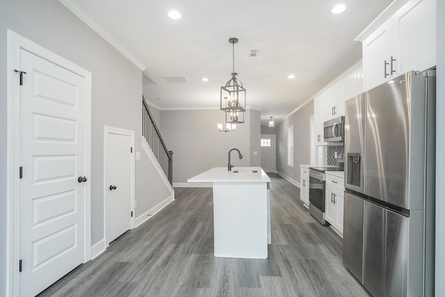 kitchen featuring sink, hanging light fixtures, appliances with stainless steel finishes, a center island with sink, and white cabinets