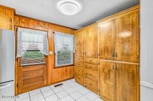 doorway to outside with light tile patterned floors, visible vents, and wood walls