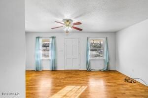 unfurnished room with a textured ceiling and wood finished floors