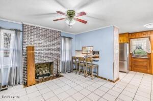 living room with ornamental molding, light tile patterned floors, a fireplace, and ceiling fan