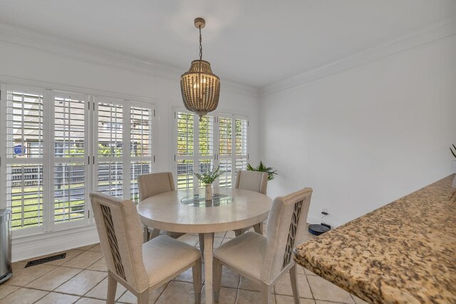 tiled dining space with a chandelier and crown molding