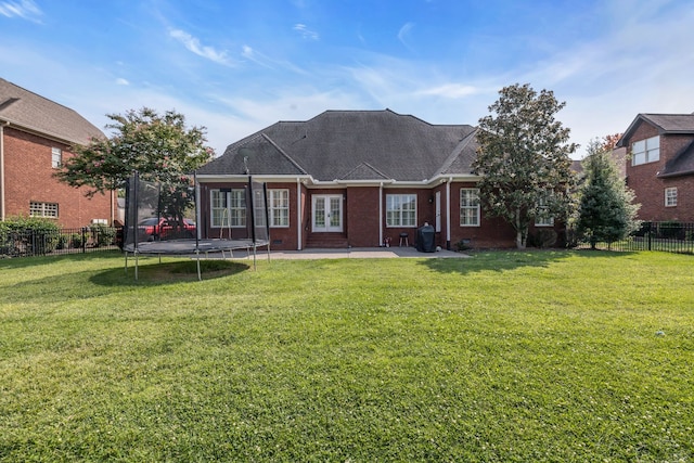 rear view of property with a lawn, a patio, and a trampoline