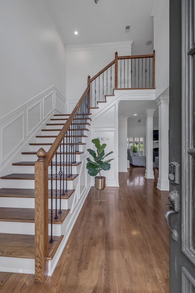 foyer entrance with ornamental molding, decorative columns, and dark hardwood / wood-style floors