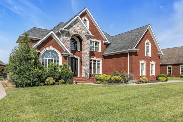 traditional-style house with brick siding, a shingled roof, and a front yard