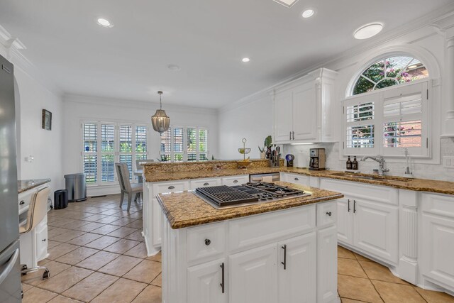 kitchen with light stone countertops, stainless steel gas cooktop, a center island, kitchen peninsula, and sink