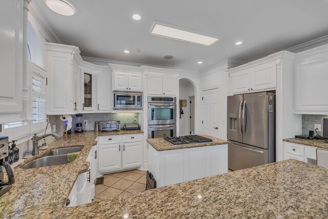 kitchen with light stone countertops, a kitchen island, stainless steel appliances, and white cabinets