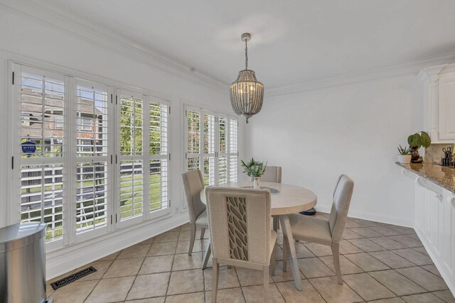 tiled dining space featuring ornamental molding, a chandelier, and a healthy amount of sunlight