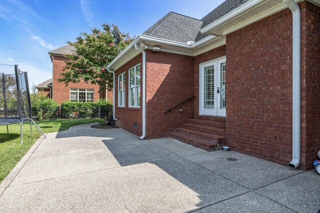 view of side of property featuring a trampoline, a yard, and a patio