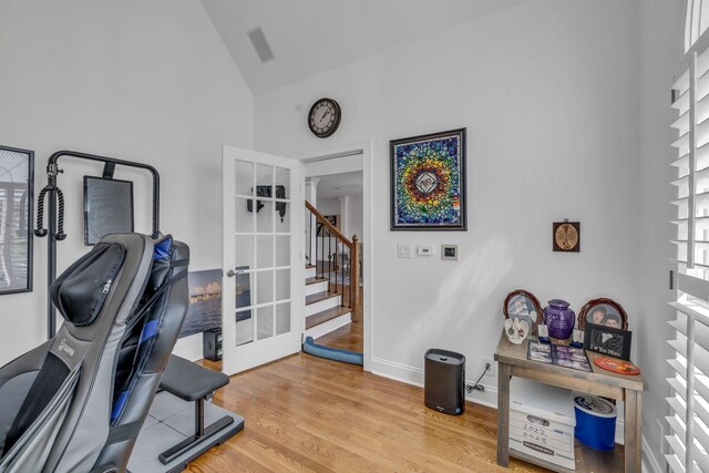 workout area featuring high vaulted ceiling, light hardwood / wood-style floors, and french doors