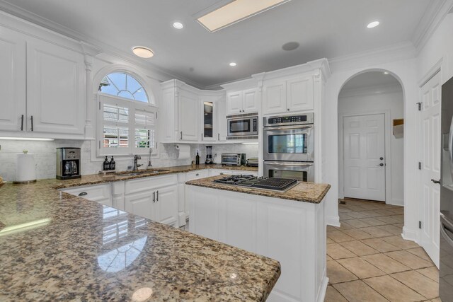 kitchen with white cabinets, appliances with stainless steel finishes, sink, and stone counters