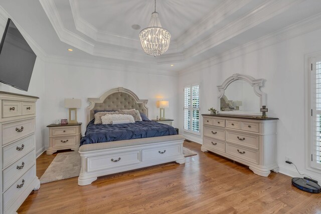 bedroom with ornamental molding, light hardwood / wood-style flooring, a raised ceiling, and a notable chandelier