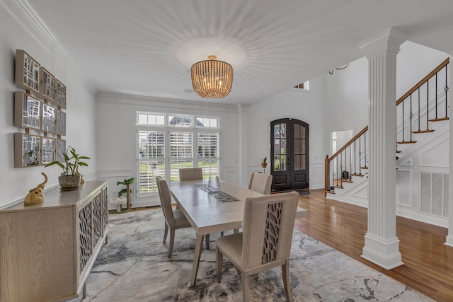 dining space featuring ornamental molding, a notable chandelier, wood-type flooring, and ornate columns