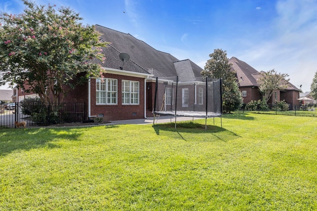 rear view of house featuring a yard, a patio, and a trampoline