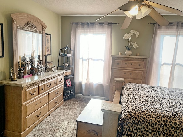 bedroom with a textured ceiling, light colored carpet, and ceiling fan