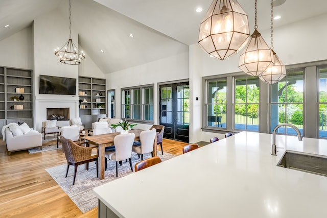 dining area featuring high vaulted ceiling, a chandelier, sink, and light hardwood / wood-style floors