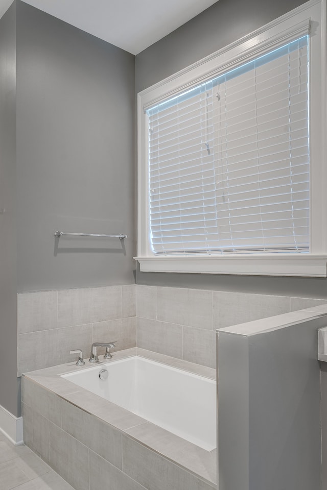 bathroom with tile patterned floors and a relaxing tiled tub