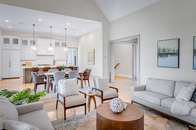 living room featuring high vaulted ceiling and light hardwood / wood-style floors