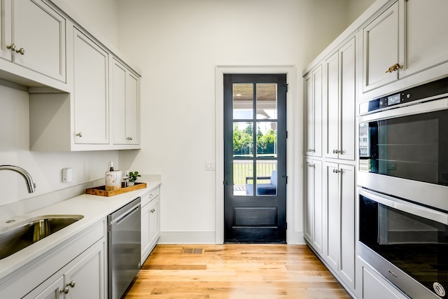 kitchen featuring light wood-type flooring, sink, and appliances with stainless steel finishes