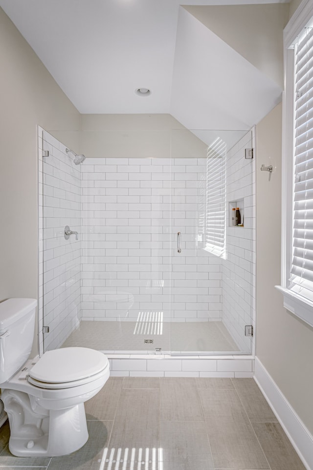 bathroom featuring toilet, a shower with door, and tile patterned floors