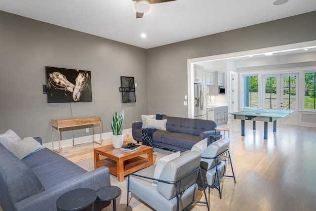 living room featuring ceiling fan, light hardwood / wood-style floors, and french doors